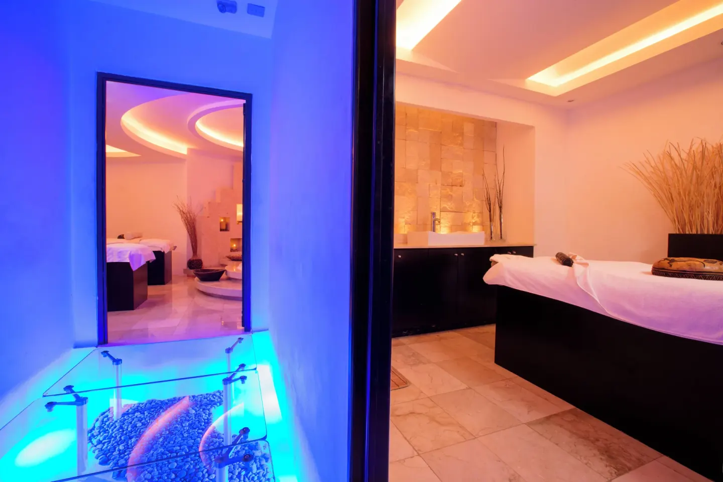 Spa treatment room and blue-lit glass walkway at Krystal Grand Cancun.