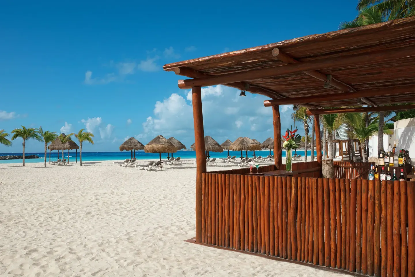 Beach bar beside white sand, palapas, and turquoise water at Krystal Grand Cancun.