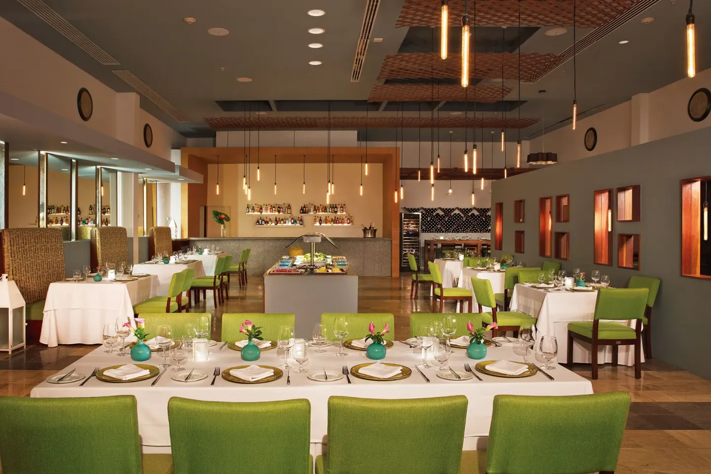 Dining room with green chairs, buffet island, and bar at Krystal Grand Cancun.