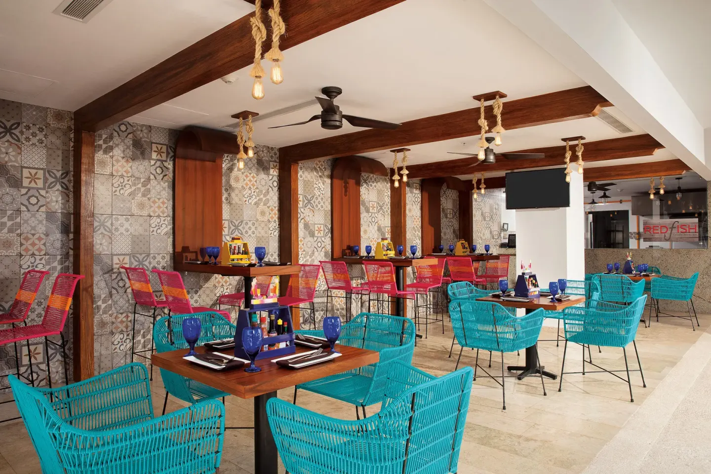 Red Fish dining area with turquoise chairs and patterned tile walls at Krystal Grand Cancun.