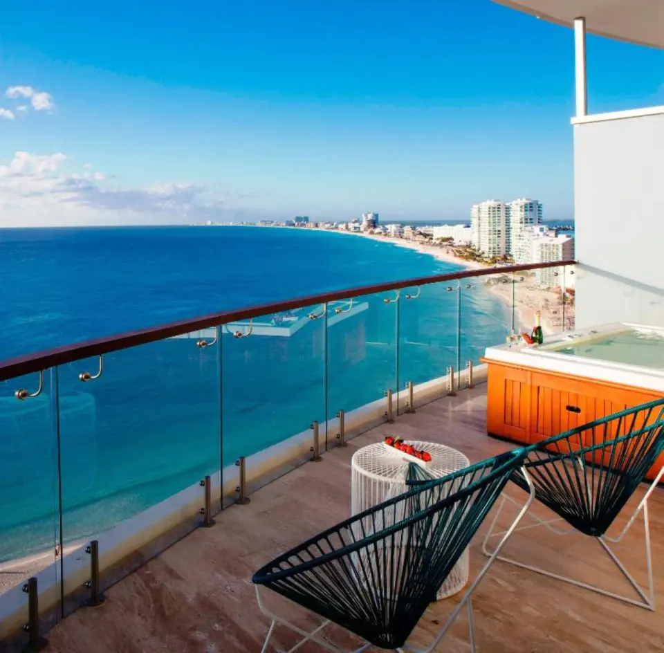 Oceanfront suite balcony with hot tub and chairs at Krystal Grand Cancun.