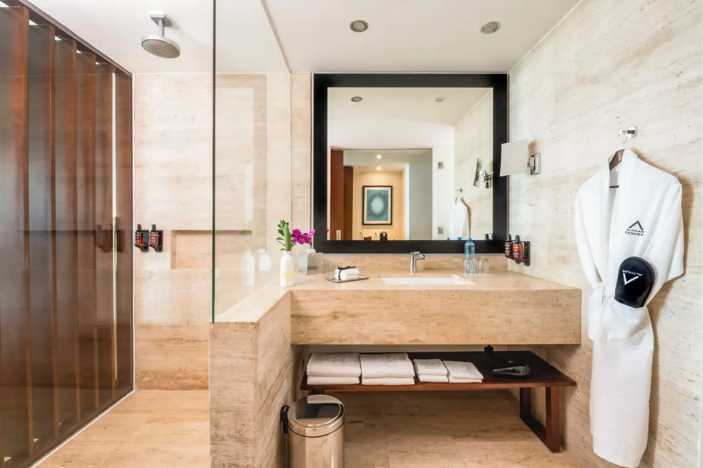 Altitude Suite bathroom with glass shower and robe at Krystal Grand Cancun.