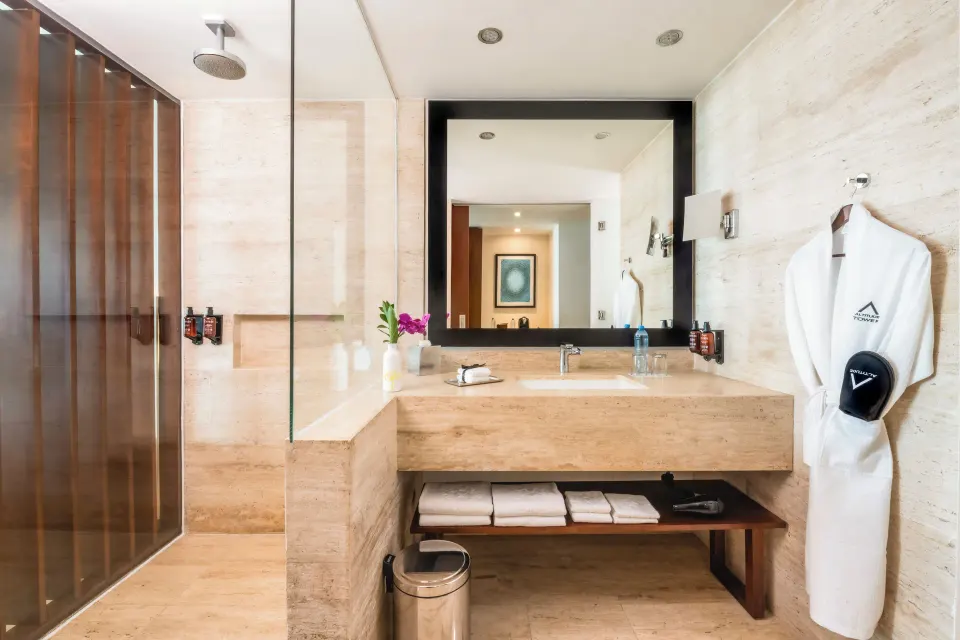 Altitude Suite bathroom with glass shower and robe at Krystal Grand Cancun.