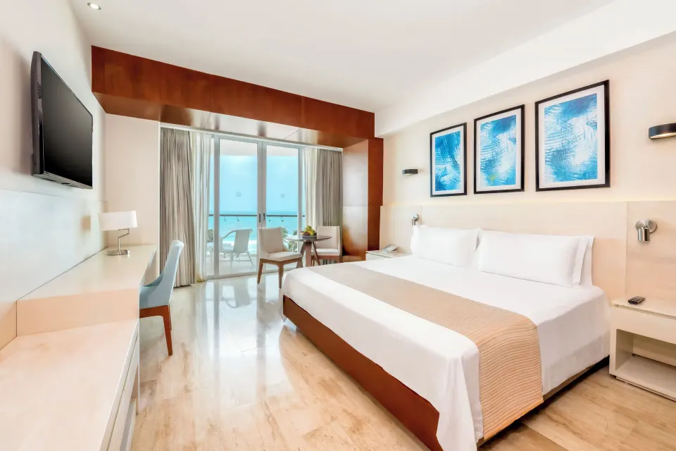 King bed with desk, TV, and balcony doors in an Altitude Suite at Krystal Grand Cancun.