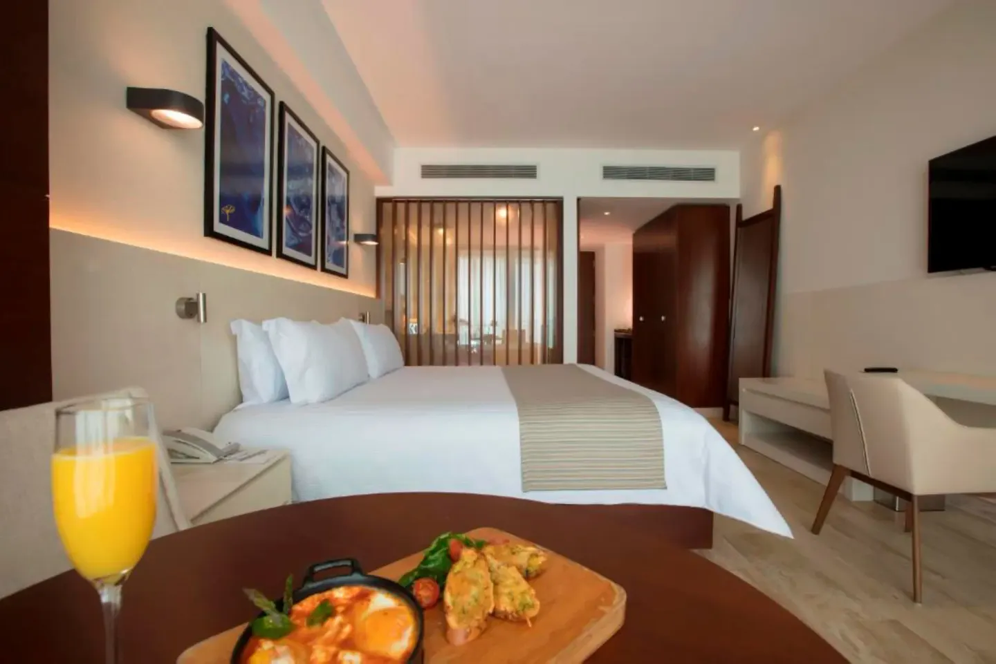 King bed and breakfast tray on a table in an Altitude Suite at Krystal Grand Cancun.