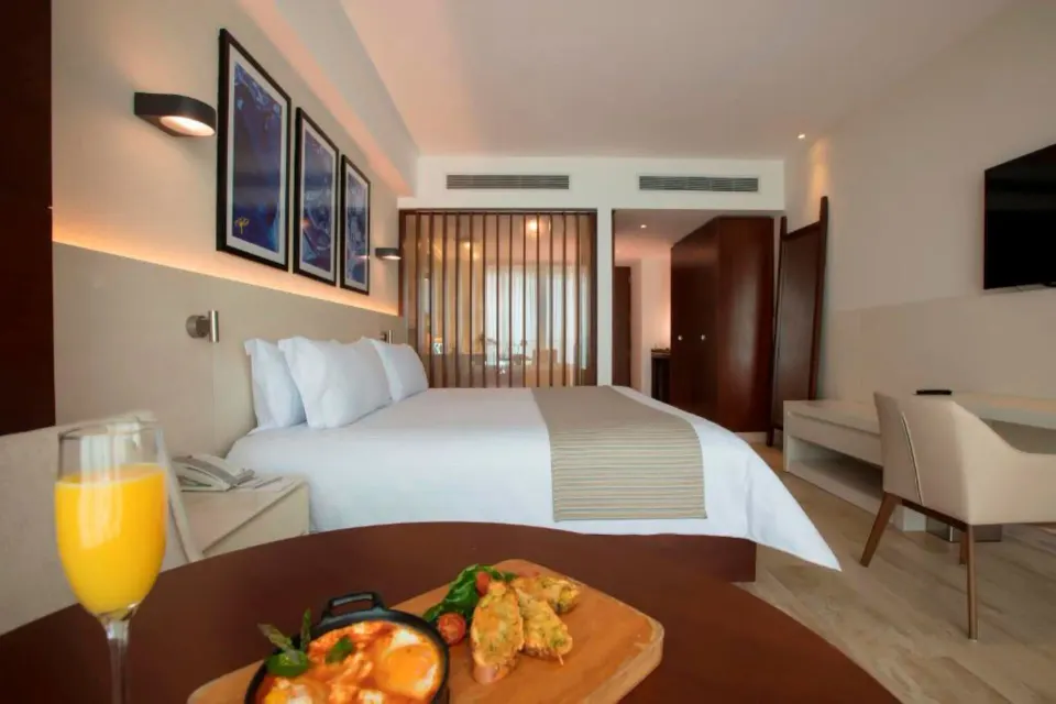 King bed and breakfast tray on a table in an Altitude Suite at Krystal Grand Cancun.