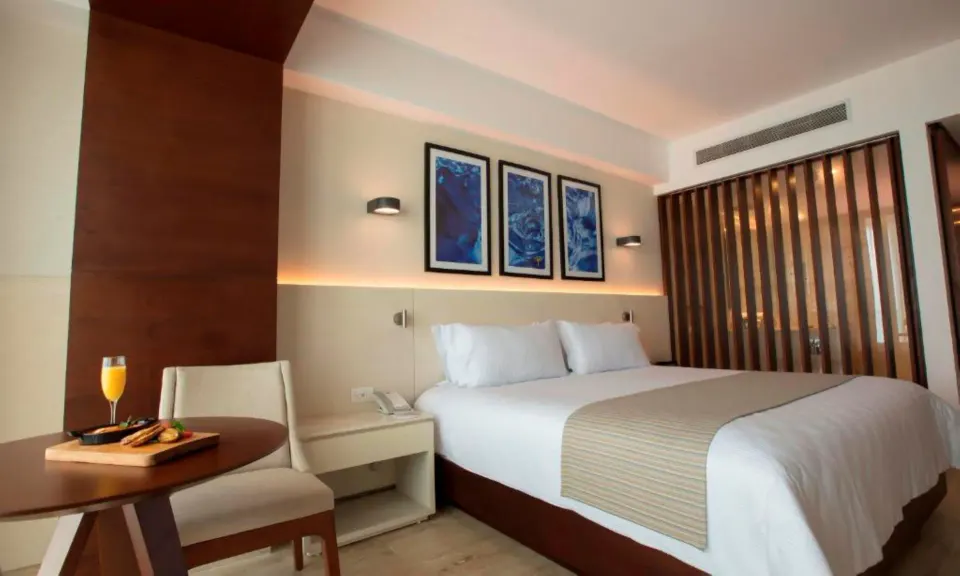 King bed and small dining table in an Altitude Suite Boulevard View at Krystal Grand Cancun.