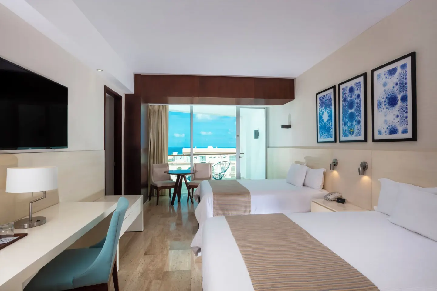 Two double beds face a desk and balcony doors in an Altitude Suite Boulevard View at Krystal Grand Cancun.