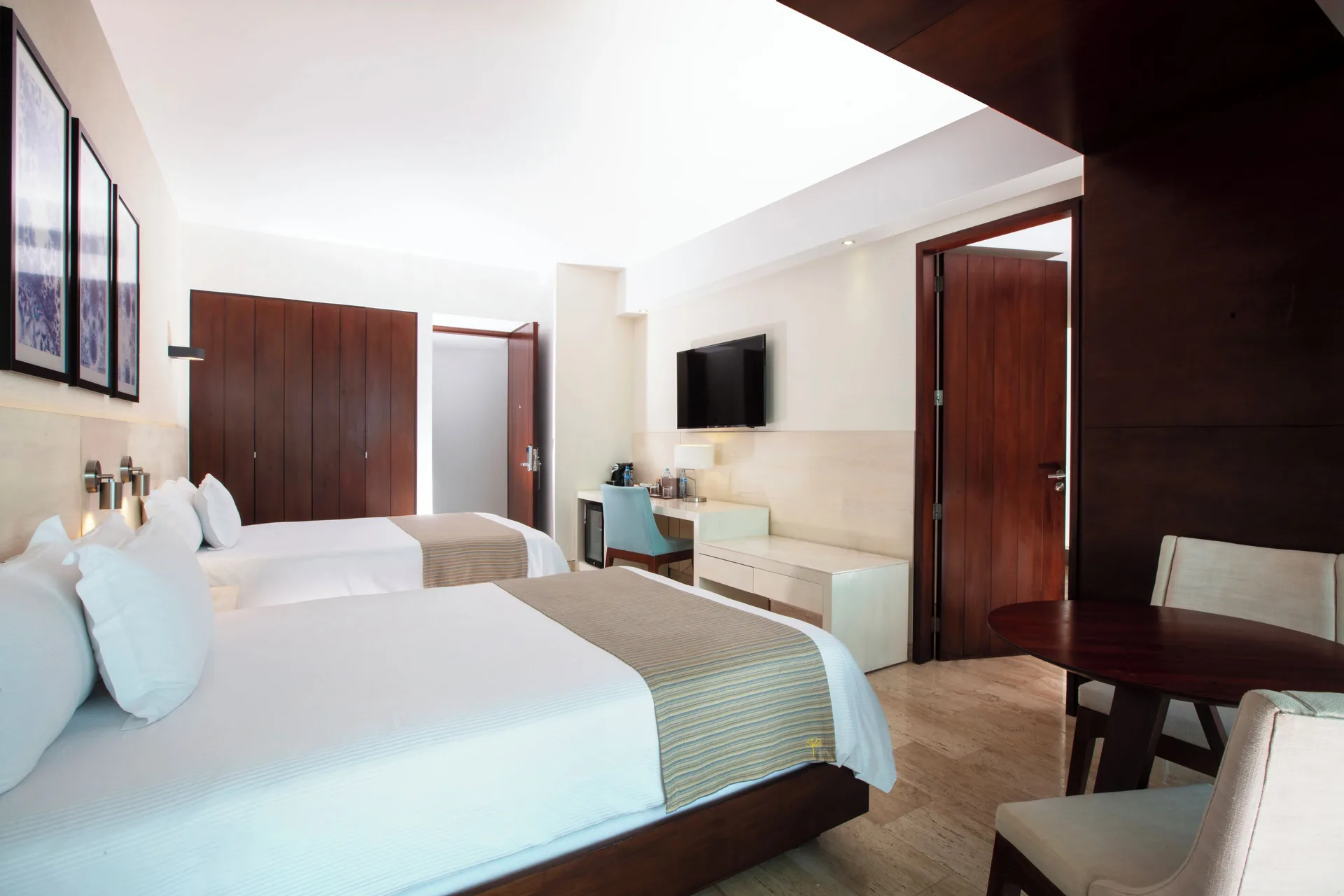 Two double beds and a work desk in an Altitude Suite Boulevard View at Krystal Grand Cancun.