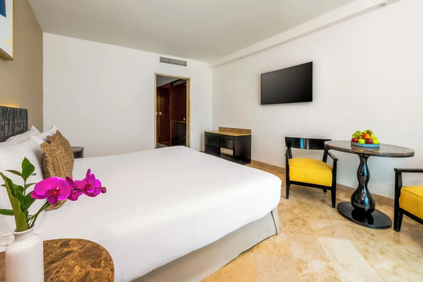 Deluxe Room Ocean View king bed with table and wall TV at Krystal Grand Cancun.