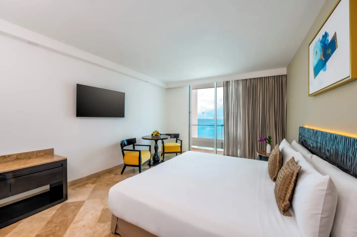 Deluxe Room Ocean View king bed and seating nook at Krystal Grand Cancun.