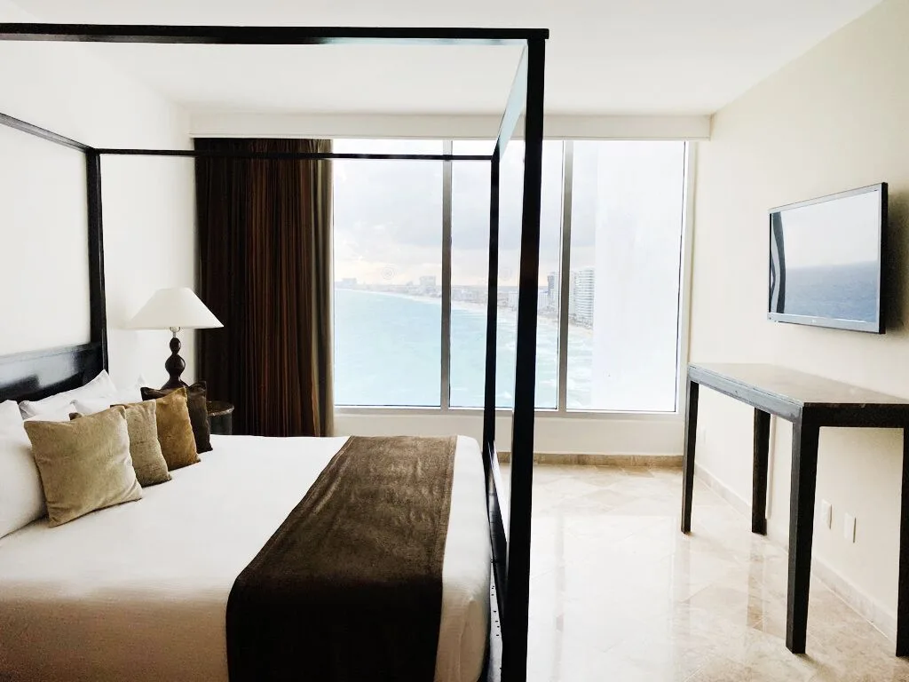 Presidential Room Ocean View king bed with TV and coastline windows at Krystal Grand Cancun.