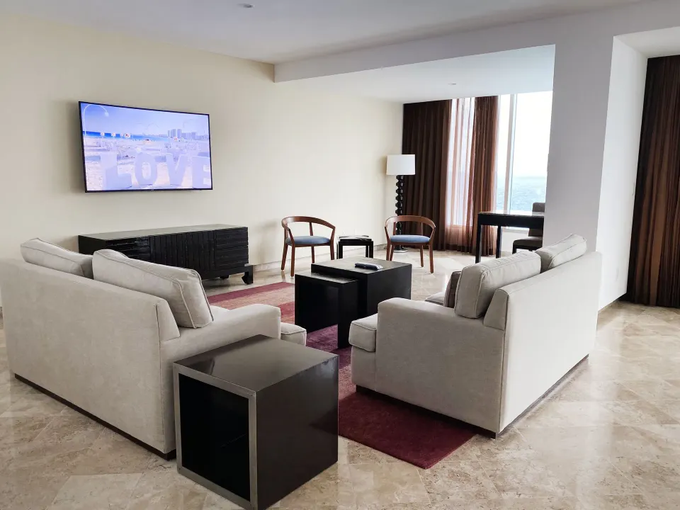 Presidential Room Ocean View lounge with sofas and wall TV at Krystal Grand Cancun.