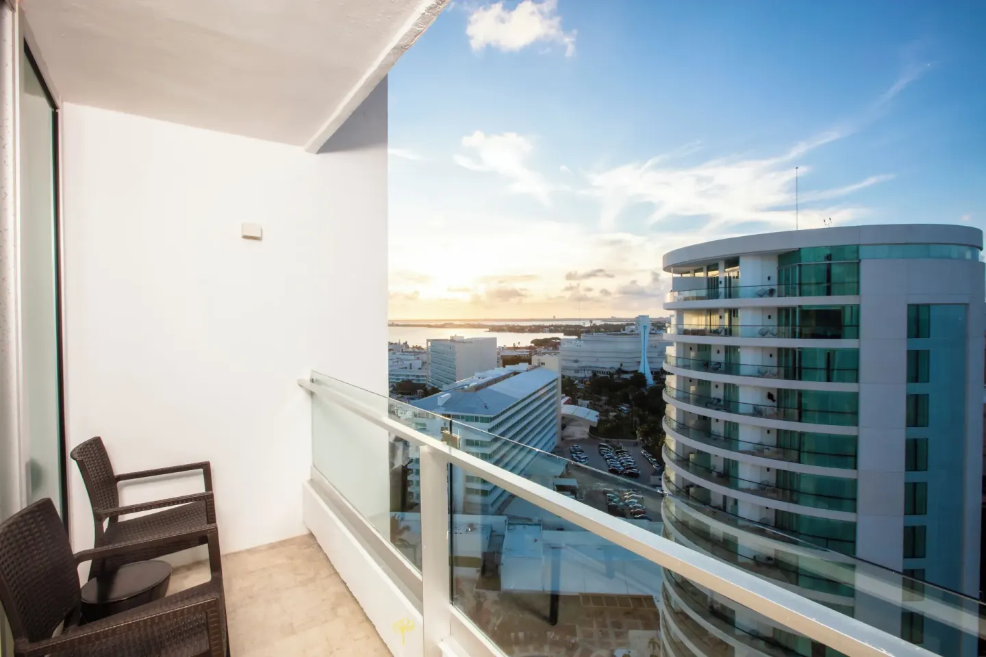 Standard Room balcony with chairs and city view at Krystal Grand Cancun.