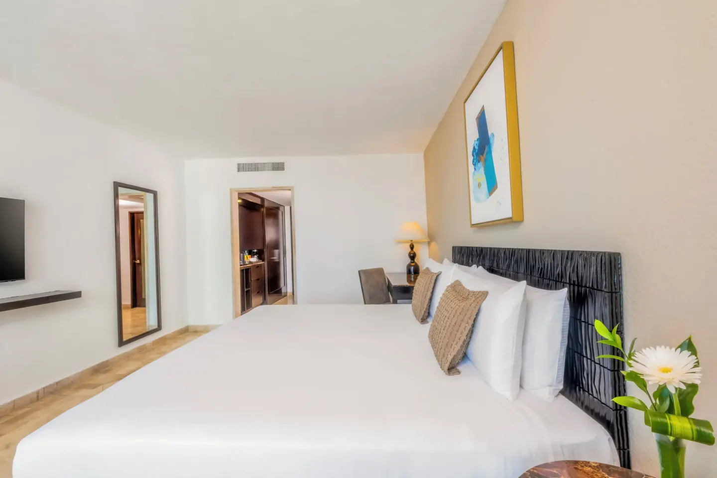 Standard Room king bed with wall mirror and TV at Krystal Grand Cancun.