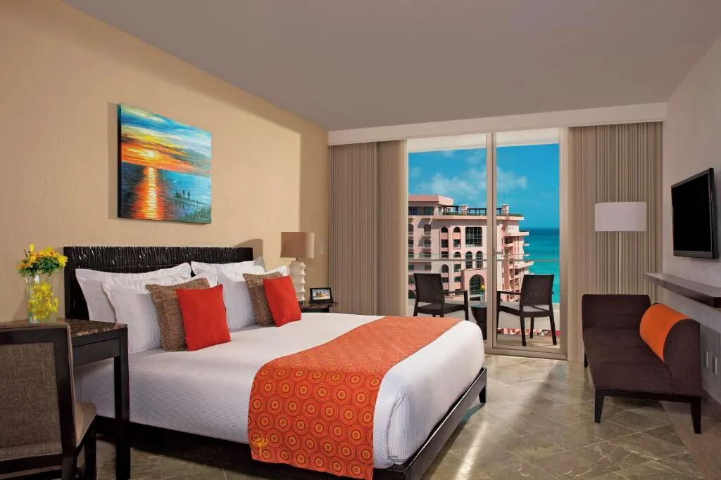 Standard Room king bed with balcony seating and partial ocean view at Krystal Grand Cancun.