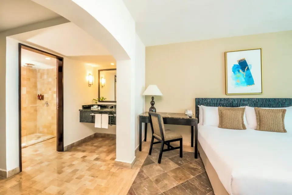 Standard Room king bed with desk and open bathroom area at Krystal Grand Cancun.