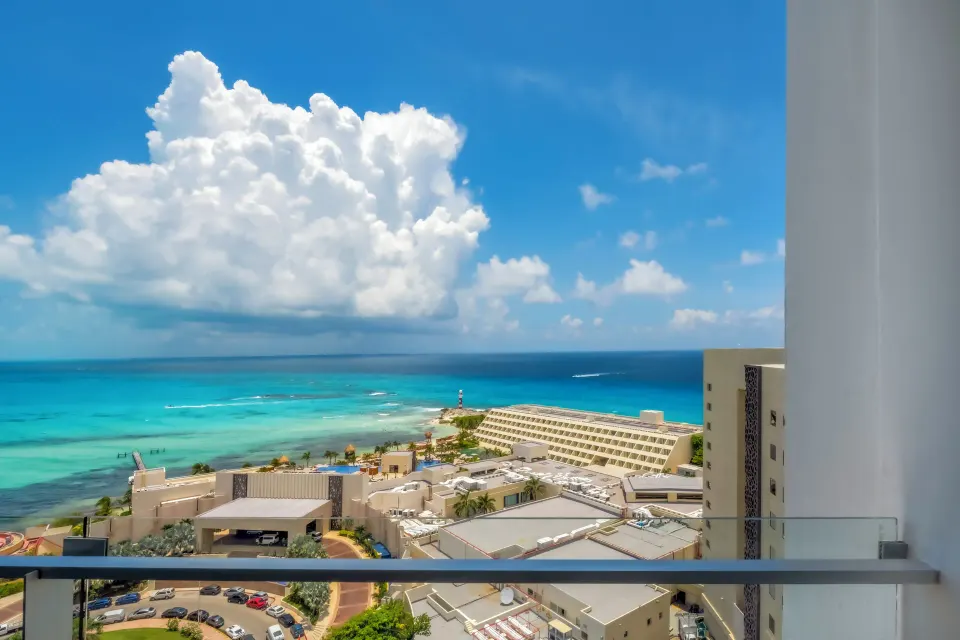 Standard Room balcony view of turquoise ocean and nearby rooftops at Krystal Grand Cancun.