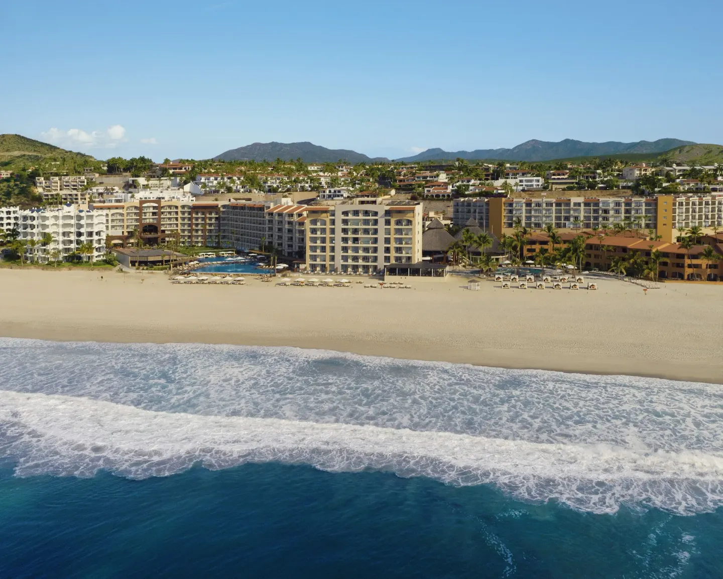 Aerial beachfront view of surf, sand, and resort buildings at Krystal Grand Los Cabos.