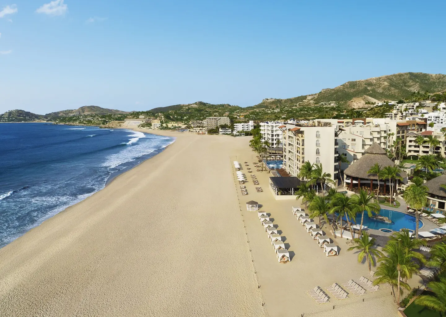 Beachfront resort, lounge chairs, pool, and coastline at Krystal Grand Los Cabos.