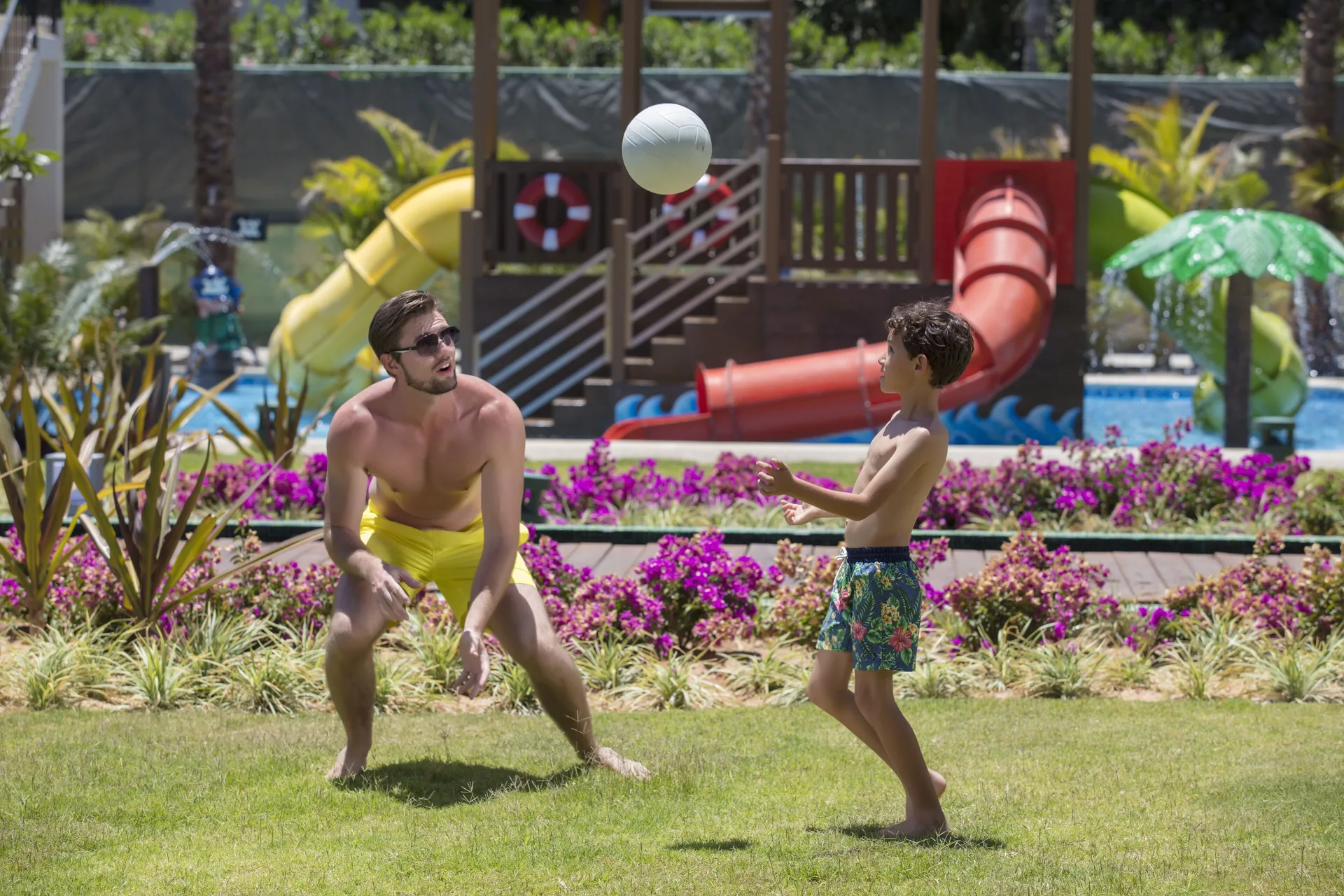 Adult and child playing volleyball near water slides at Krystal Grand Los Cabos.