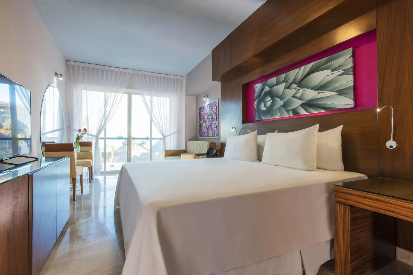 Guest room with king bed, balcony doors and seating at Krystal Grand Los Cabos.