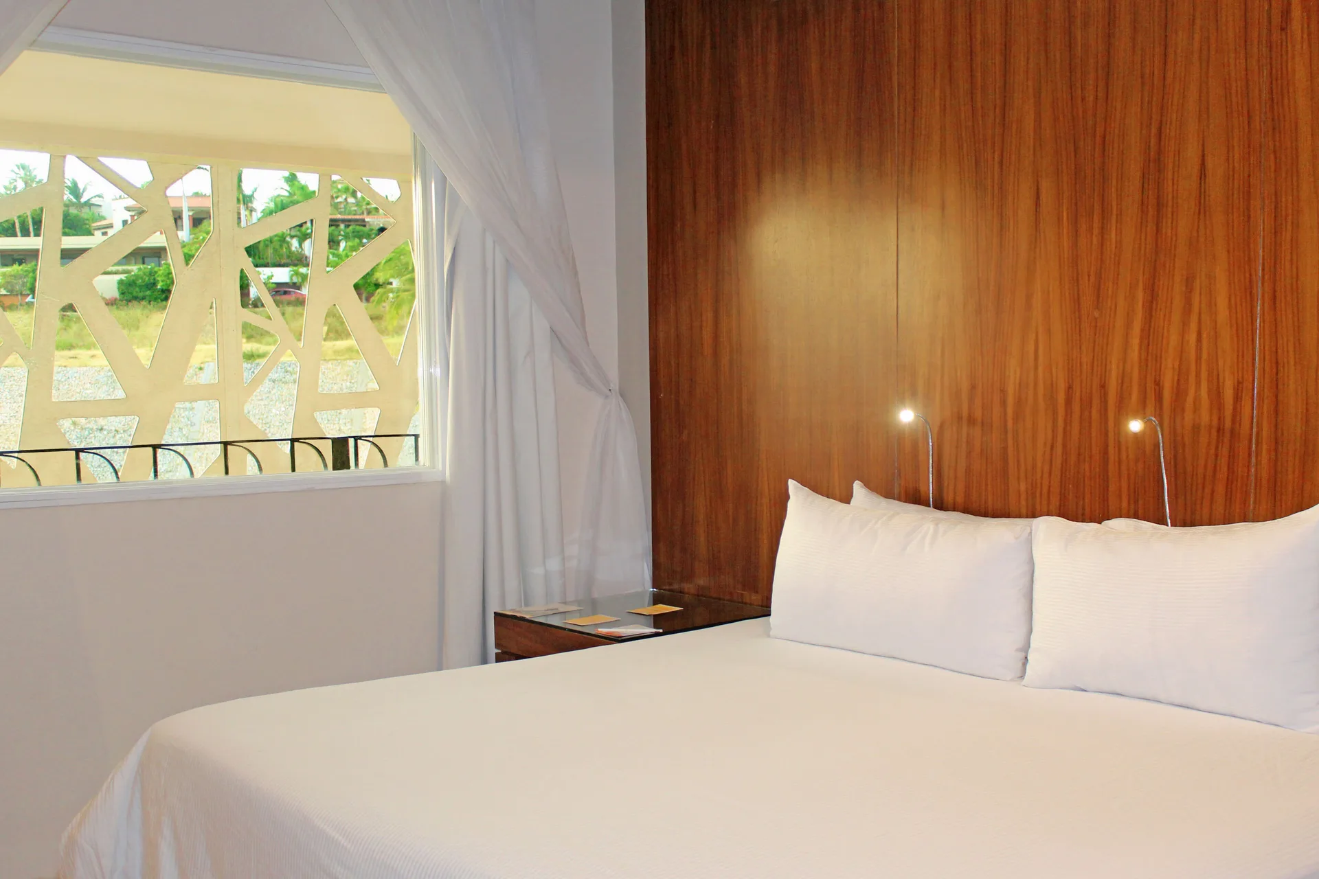 King bed beside a curtained window in a guest room at Krystal Grand Los Cabos.