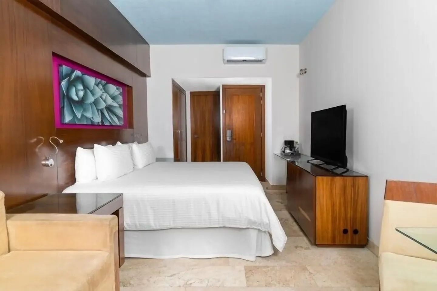 King bed guest room with wood finishes and TV at Krystal Grand Los Cabos.