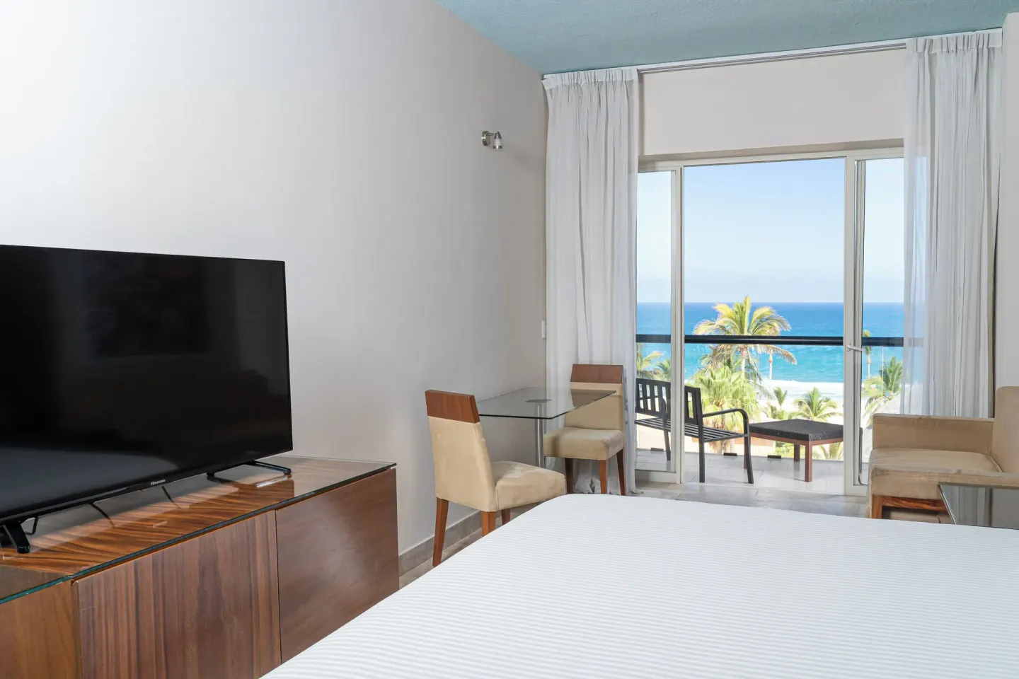 Ocean view guest room with bed, TV, and balcony at Krystal Grand Los Cabos.