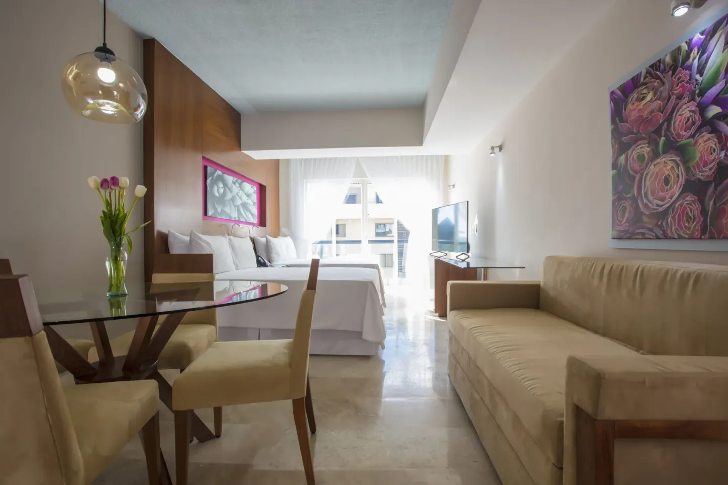 Guest room with king bed, sofa, dining table and balcony light at Krystal Grand Los Cabos.