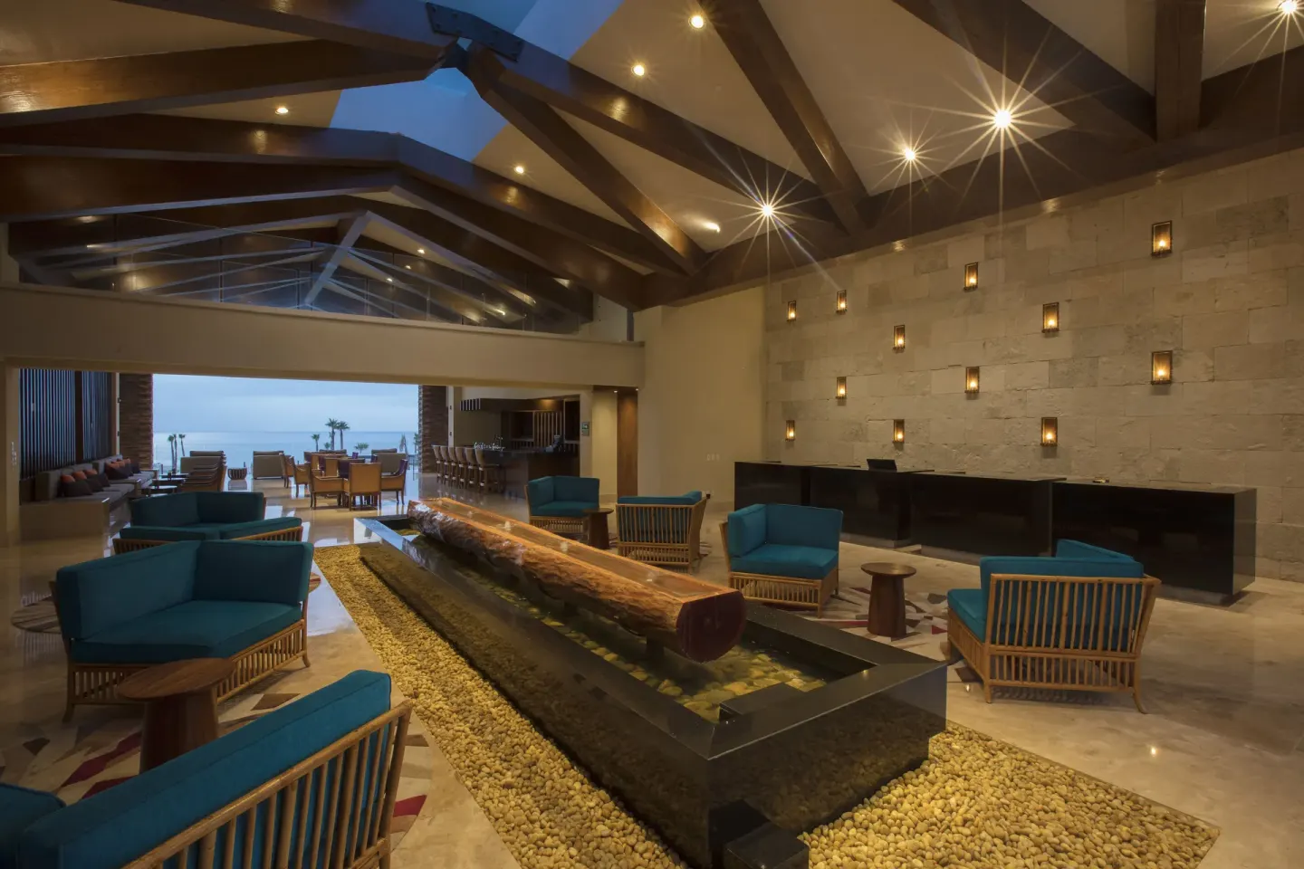 Lobby lounge with log water feature and stone wall lights at Krystal Grand Los Cabos.