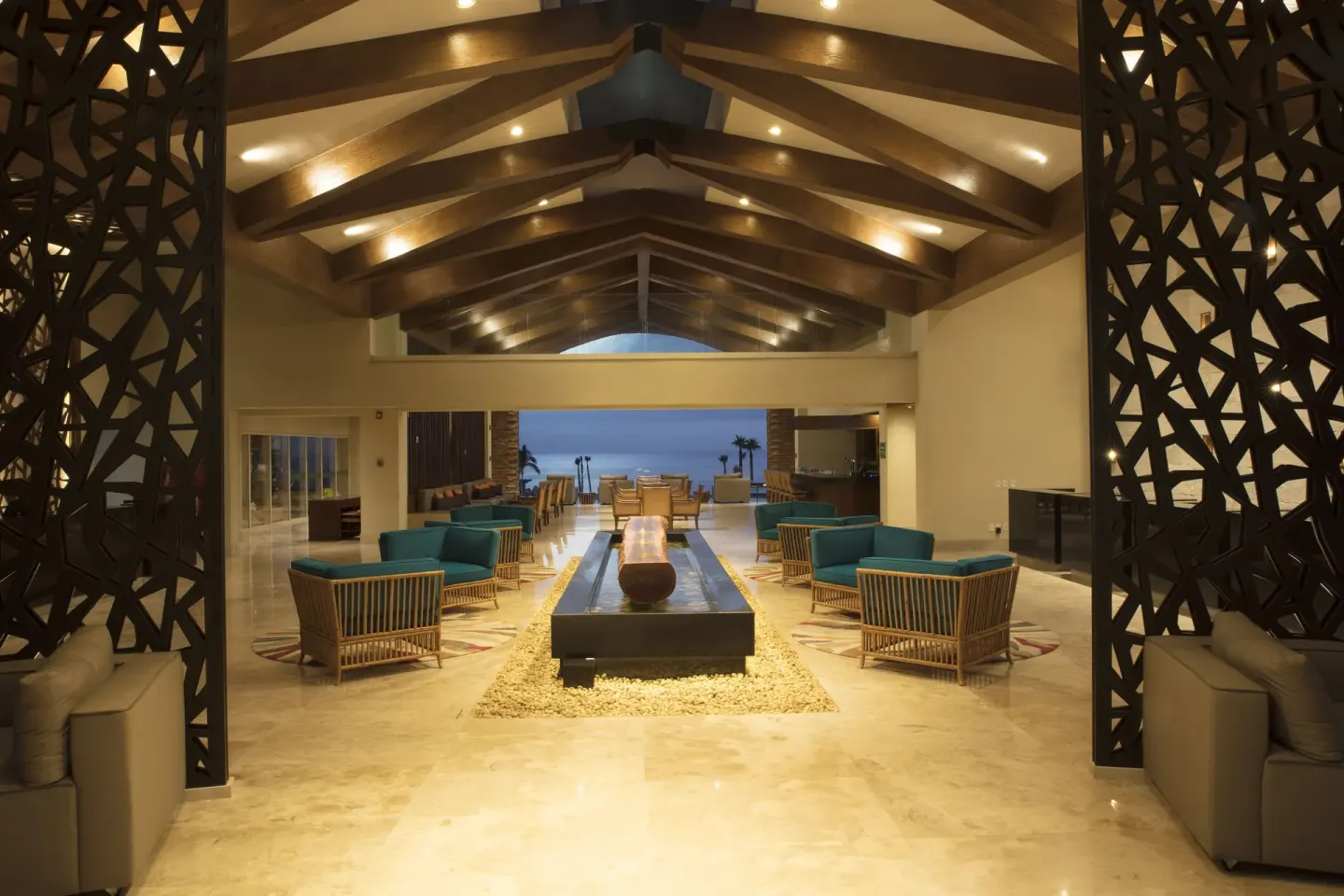 Open-air lobby lounge with teal seating and ocean view at Krystal Grand Los Cabos.