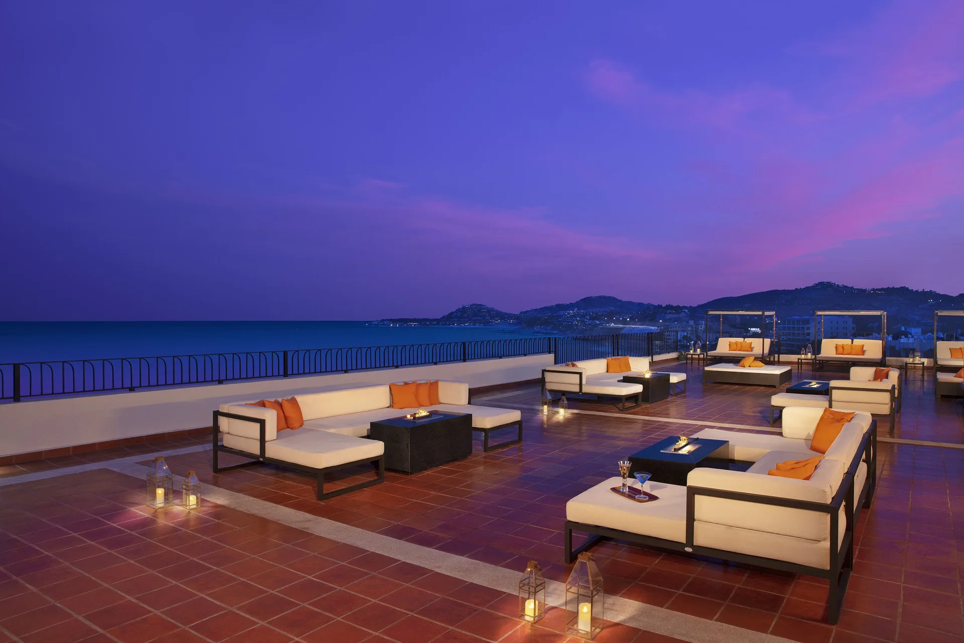 Rooftop lounge seating at twilight overlooking the ocean at Krystal Grand Los Cabos.