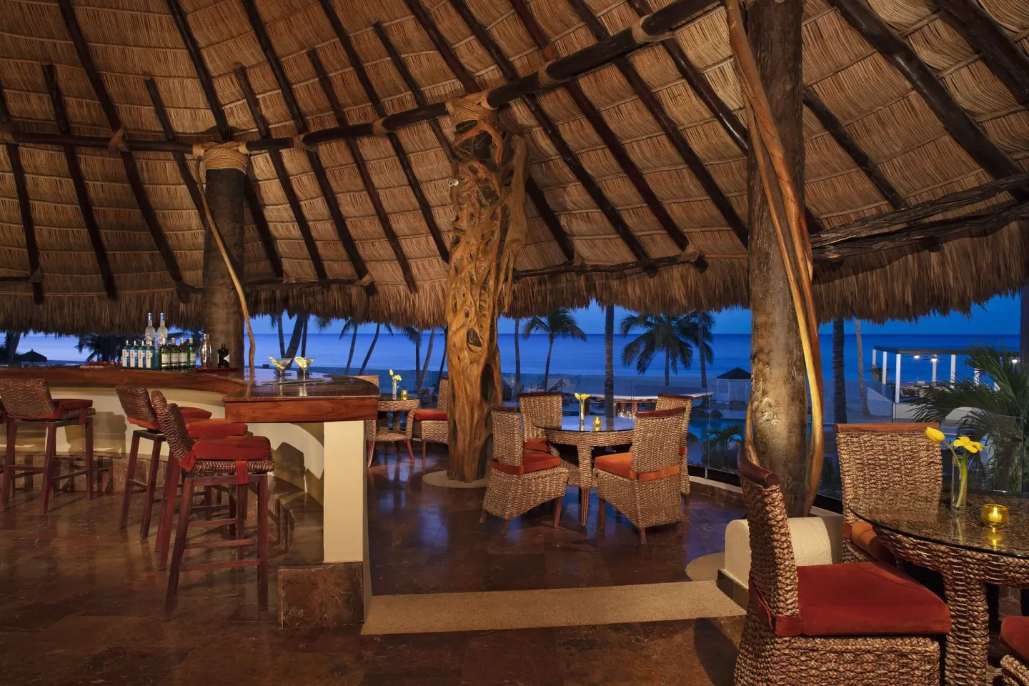 Thatched-roof bar with wicker seating and ocean views at Krystal Grand Los Cabos.