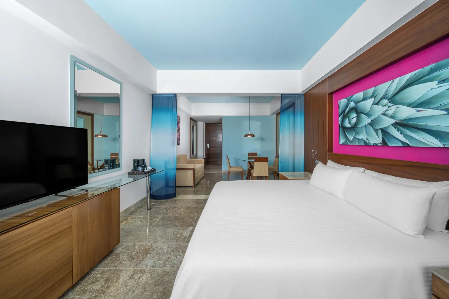 Altitude Junior Suite swimout garden view king bed at Krystal Grand Los Cabos with TV and sitting area beyond.