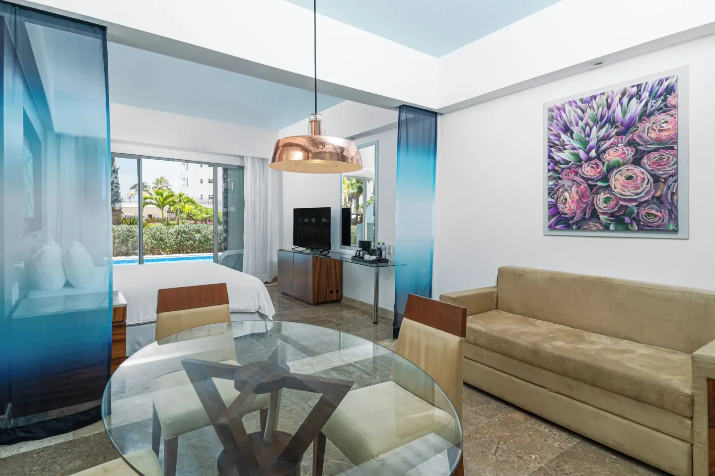 Altitude Junior Suite swimout garden view living area at Krystal Grand Los Cabos with sofa, dining table, and bed.