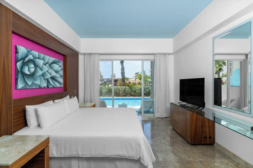 Altitude Junior Suite swimout garden view bedroom at Krystal Grand Los Cabos with pool visible through sliding doors.