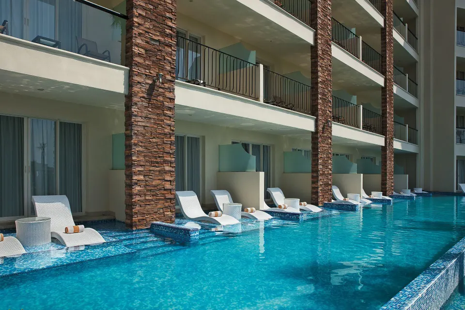 Swimout pool outside Altitude Junior Suite garden view rooms at Krystal Grand Los Cabos with loungers by terraces.