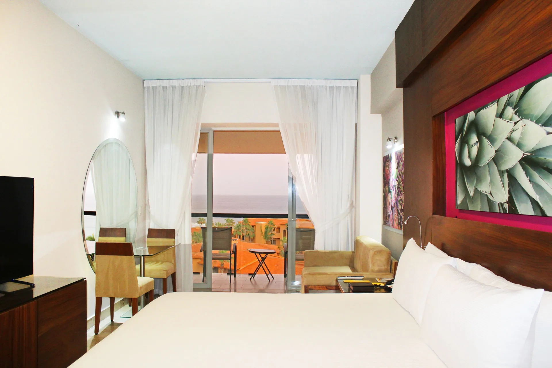 Deluxe Room king bed with sheer curtains and balcony at Krystal Grand Los Cabos.