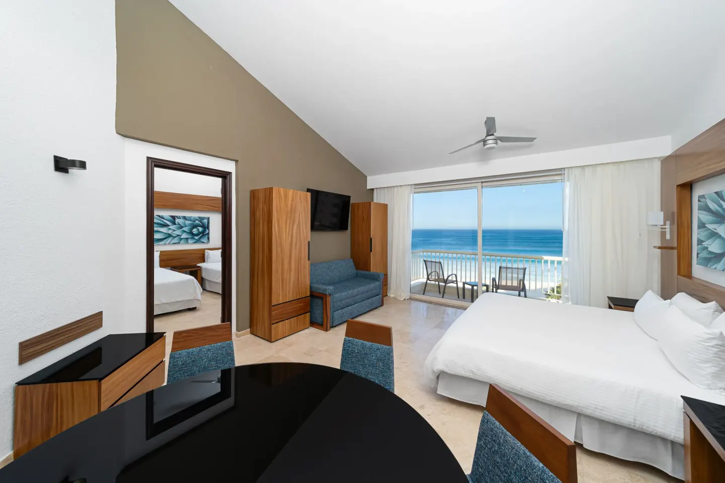 Suite Palmilla Ocean View with bed, dining table, sofa, and balcony at Krystal Grand Los Cabos.