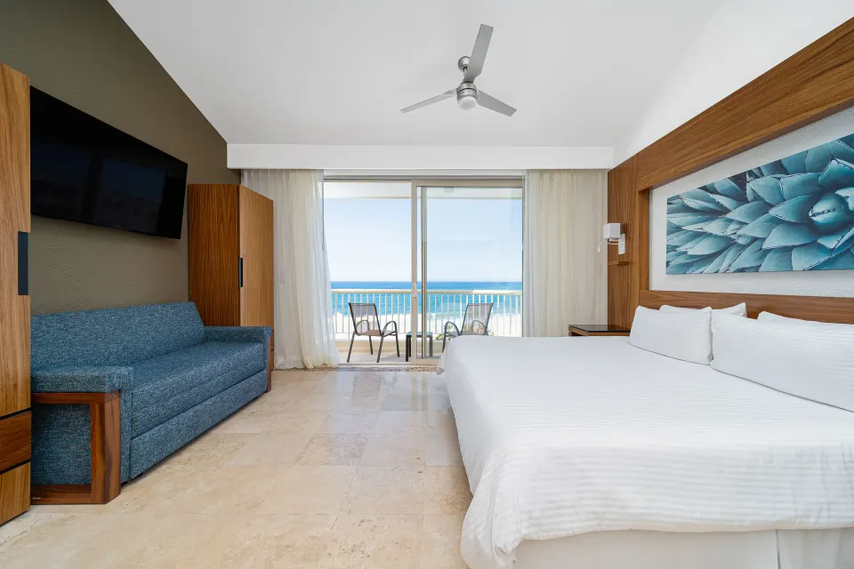 Suite Palmilla Ocean View king bed with sofa and balcony at Krystal Grand Los Cabos.