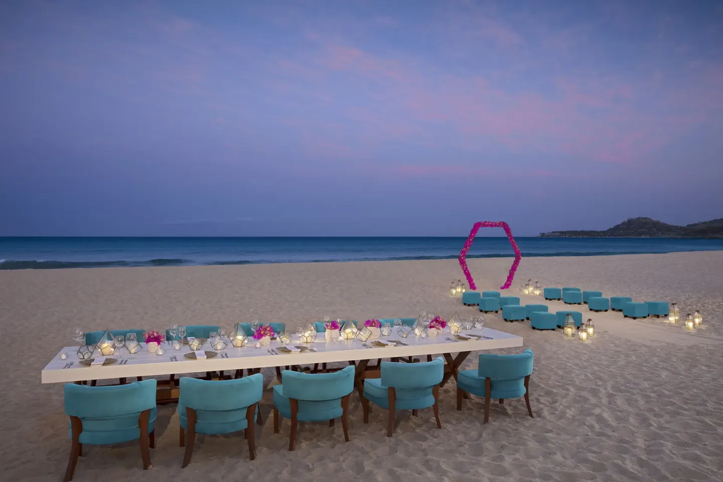 Beach dinner setup with turquoise chairs and lanterns at Krystal Grand Los Cabos.