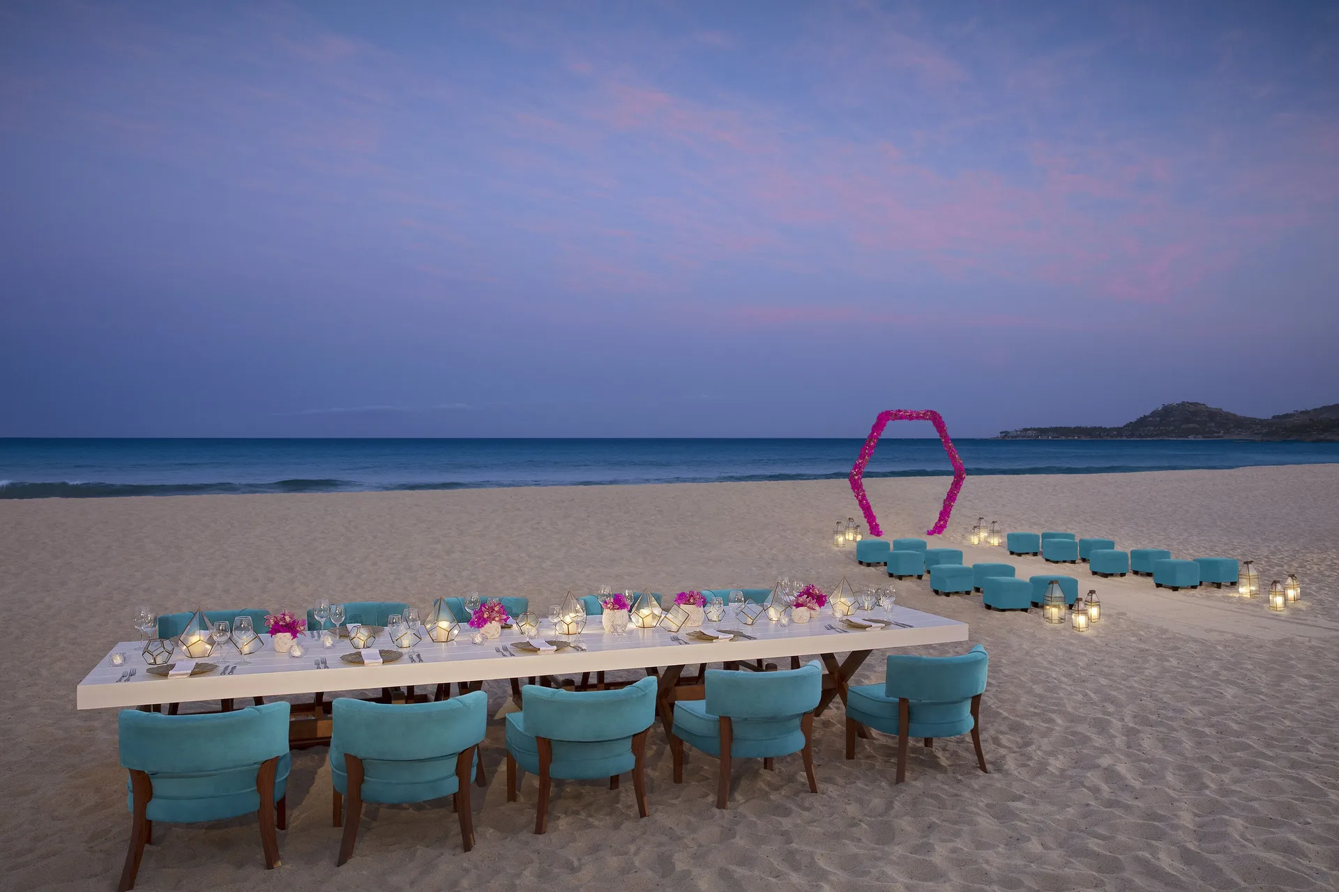 Beach dinner setup with turquoise chairs and lanterns at Krystal Grand Los Cabos.