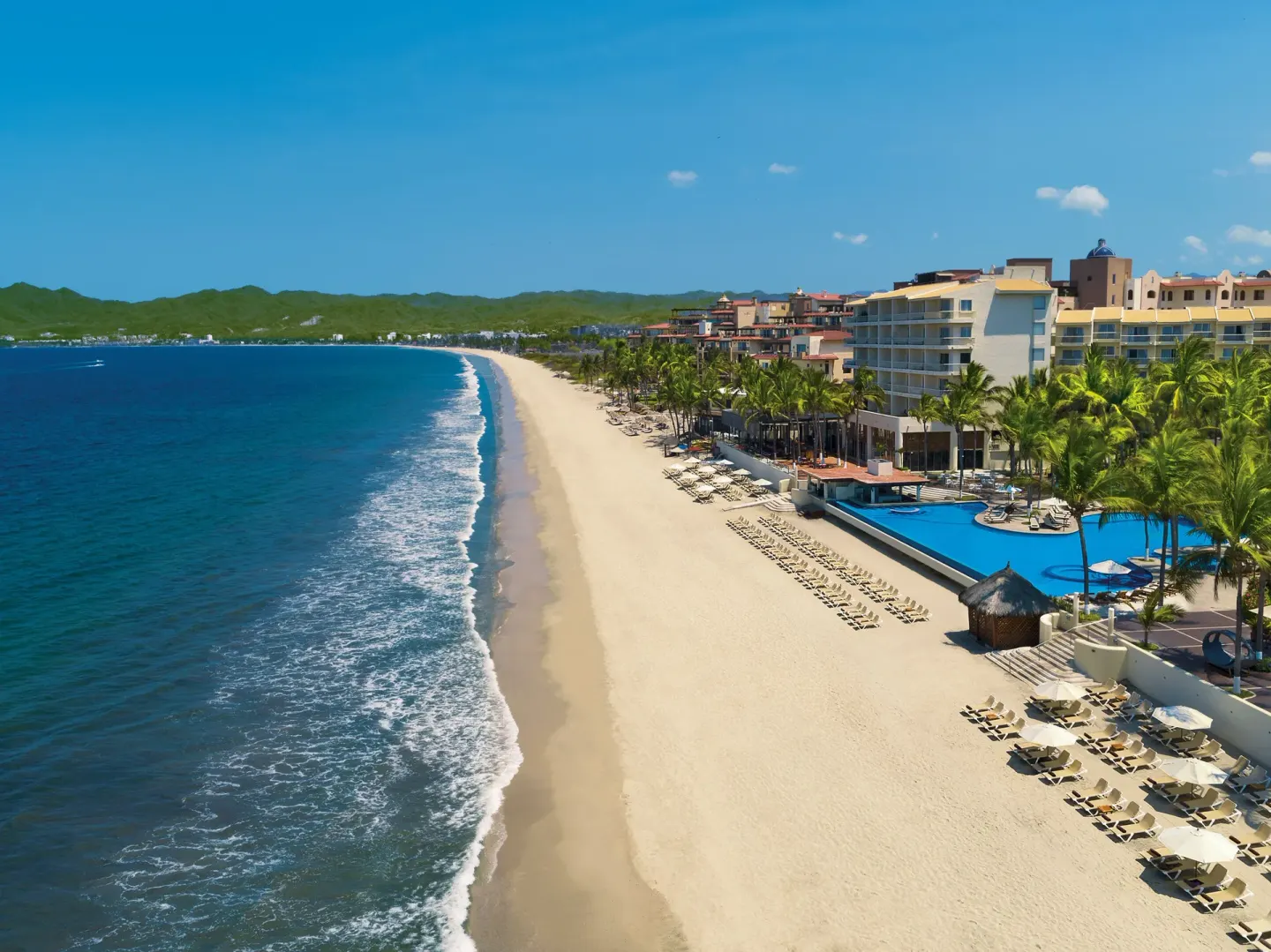 Aerial beachfront view of Krystal Grand Nuevo Vallarta with pools and loungers.