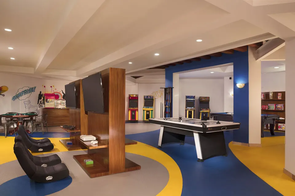 Game room with arcade machines, screens, and a pool table at Krystal Grand Nuevo Vallarta.