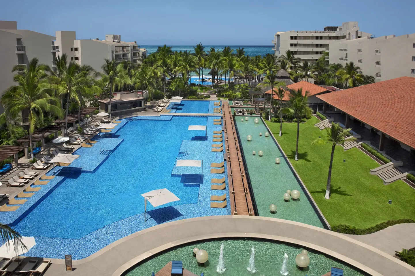 Aerial view of the main pool, palm gardens, and ocean at Krystal Grand Nuevo Vallarta.