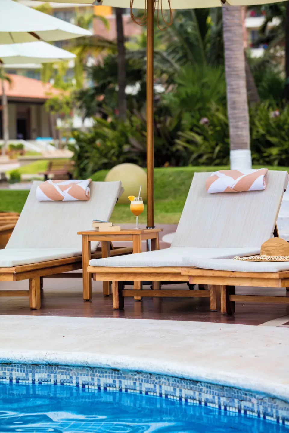 Poolside loungers with umbrellas and a drink at Krystal Grand Nuevo Vallarta.