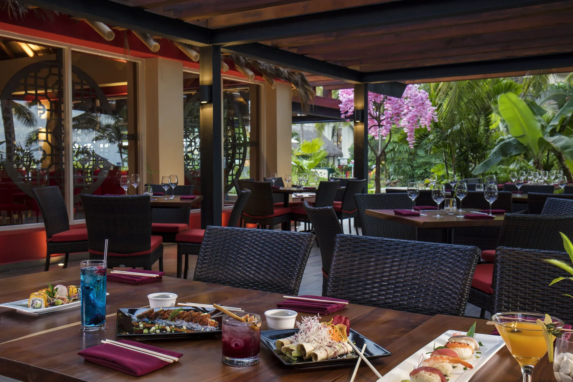 Outdoor Asian dining table with sushi, noodles, and drinks at Krystal Grand Nuevo Vallarta.