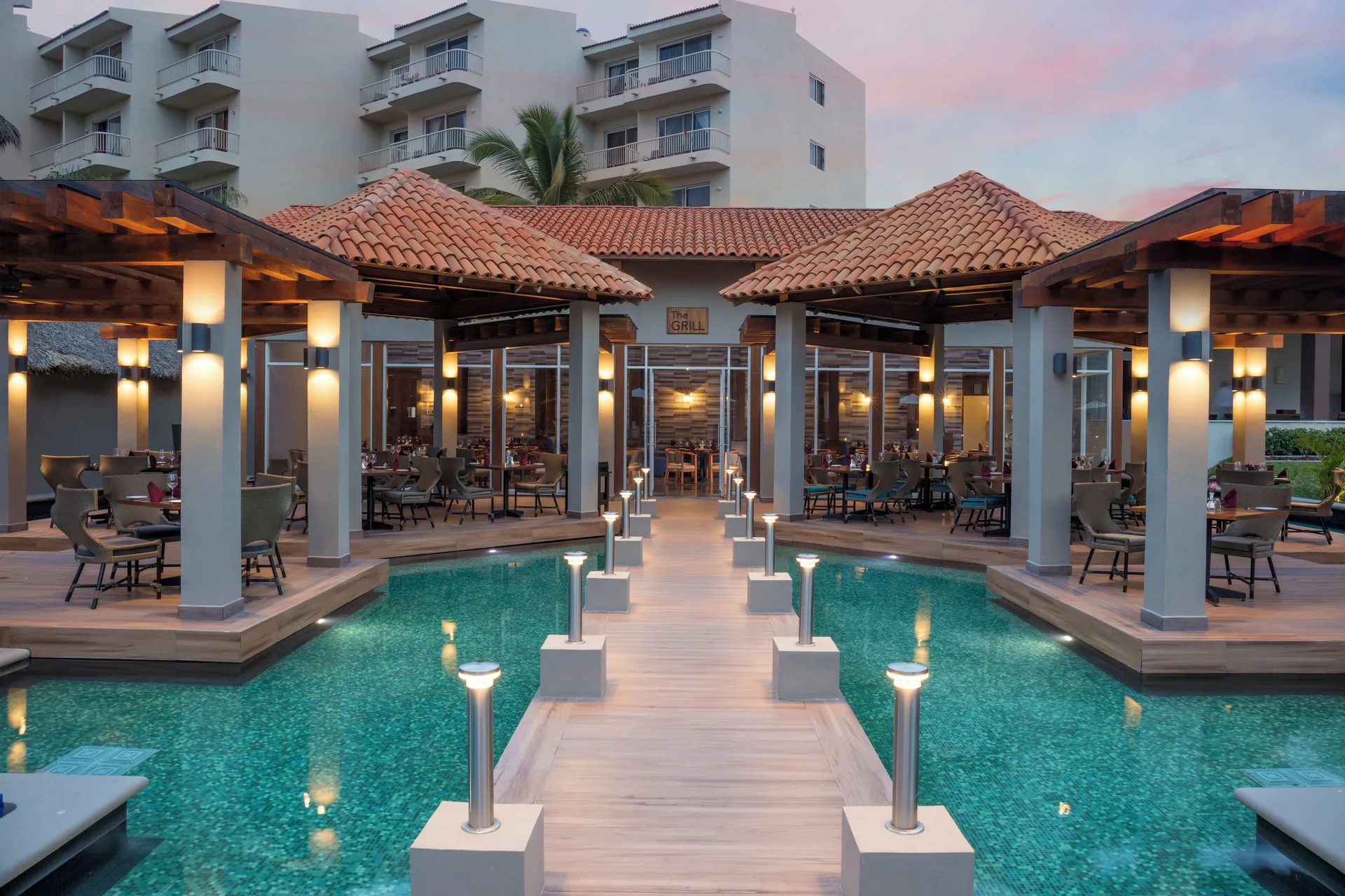 The Grill exterior with poolside dining and lit walkway at Krystal Grand Nuevo Vallarta.
