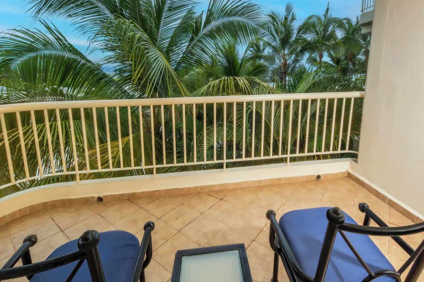 Deluxe Tropical Room View balcony with chairs and palm trees at Krystal Grand Nuevo Vallarta.